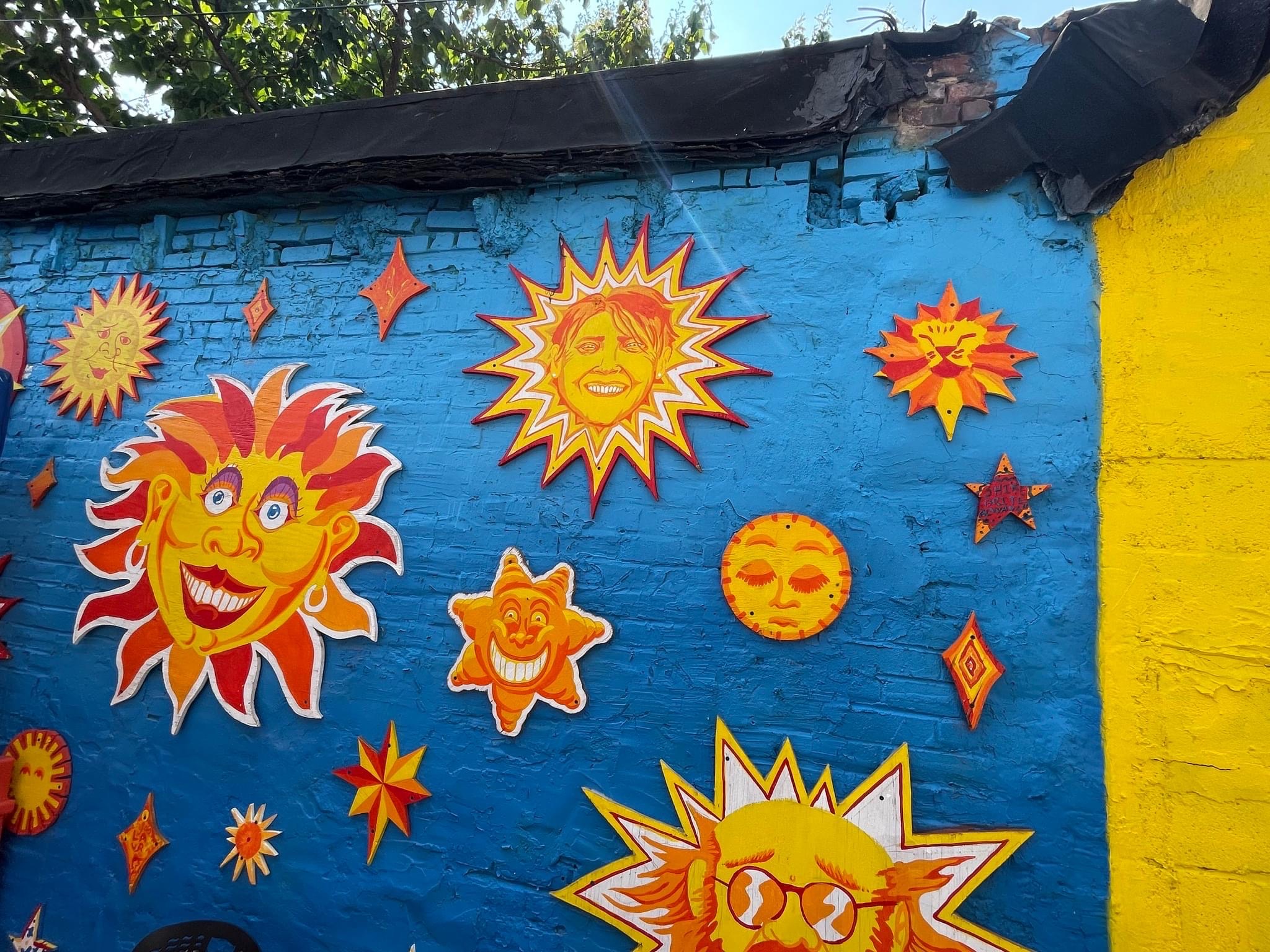 Suns with faces painted on them decorate a concrete wall