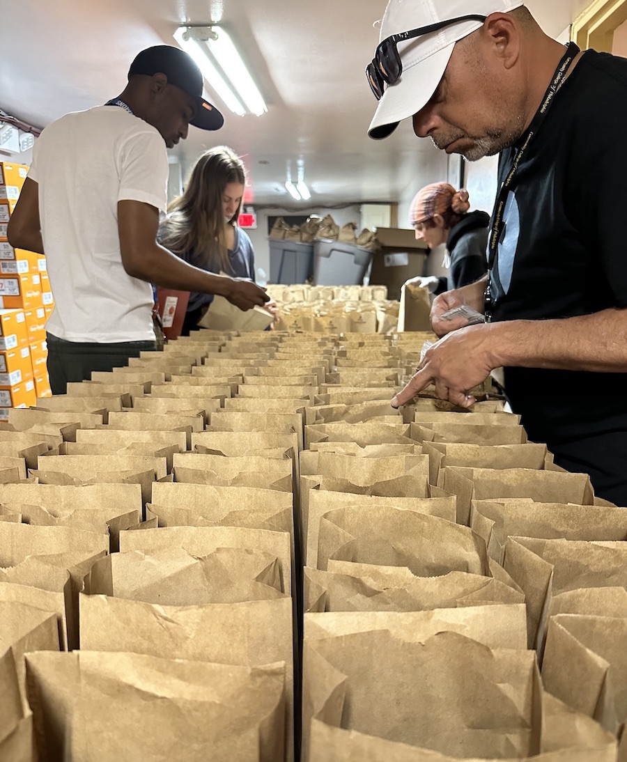 Four people assemble bags of harm reduction supplies.