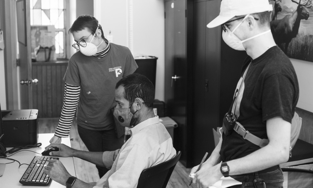 Two STEP staff members look at computer screen with a doctor. All in face masks.