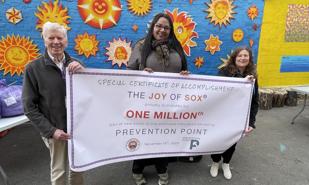 Three people hold a banner saying "one million" pairs of socks