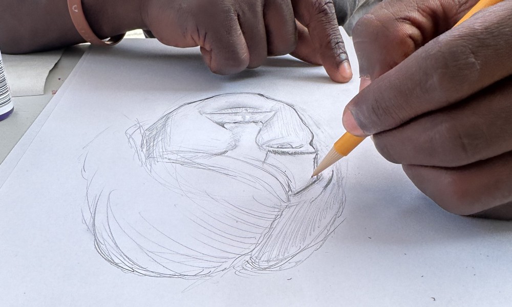 two hands. one holds a pencil and is drawing a portrait of someone with short hair.