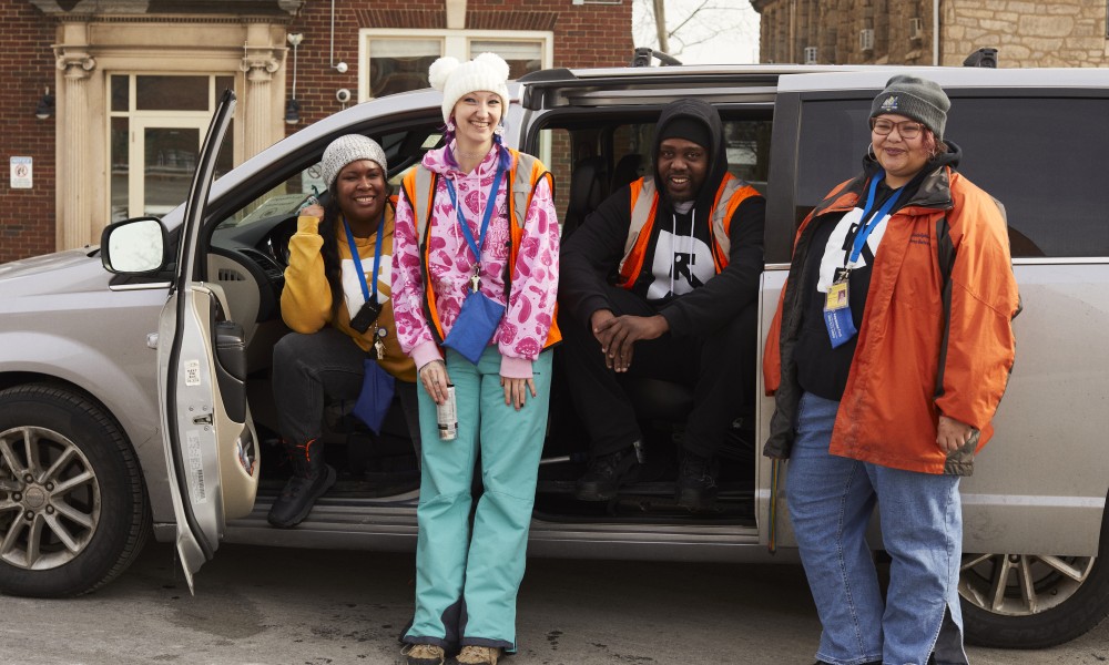 four people smile from a van