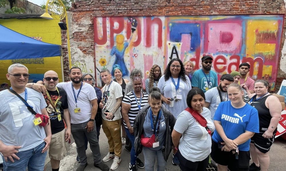 a group of PPP staff stand outside in front of a mural