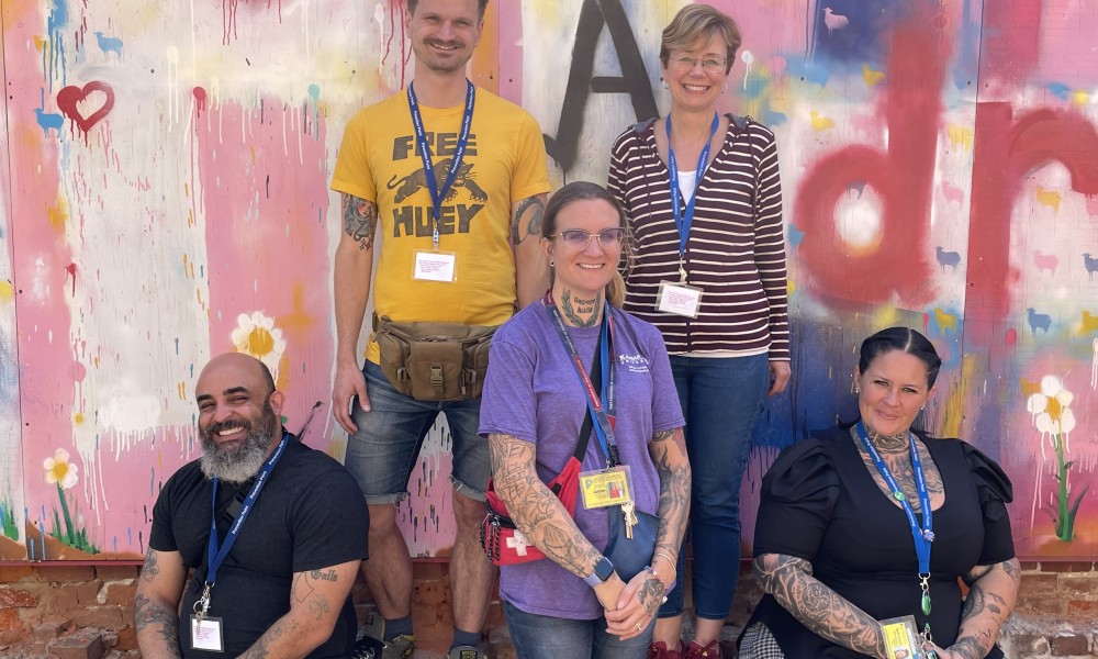 PPP's case management team smiles in front of a pink, red, blue and yellow wall