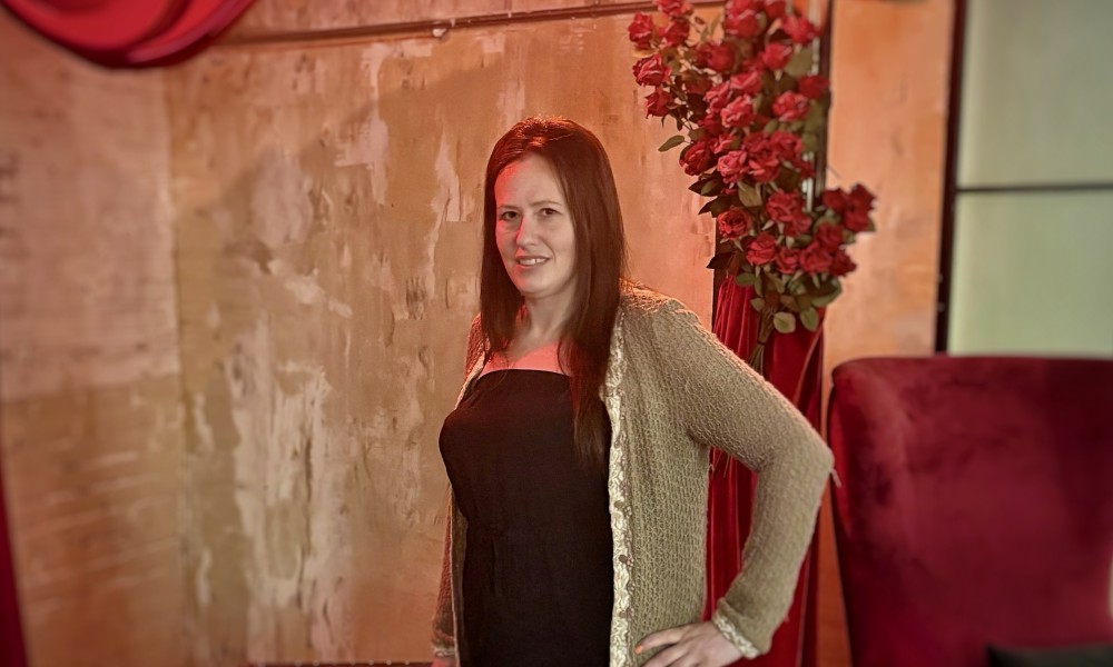 LeeAnn dressed up in a black dress with a green sweater posing for a photo at an event