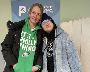Amy wears a green Eagles sweatshirt and stands with her case manager Ripley who is in a jean jacket. 