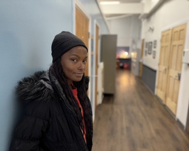 a young woman looks directly into the camera with a faint but confident smile.