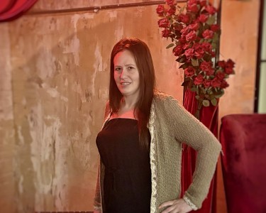 LeeAnn dressed up in a black dress with a green sweater posing for a photo at an event